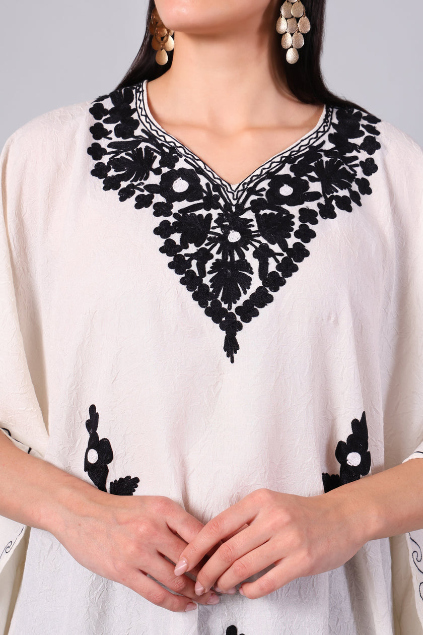 Close-up of black Kashmiri Aari floral embroidery on ivory white kaftan neckline